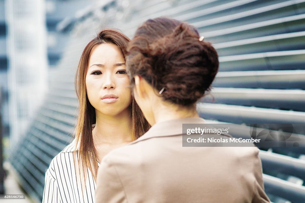 Serious young Japanese woman being scolded by her female boss