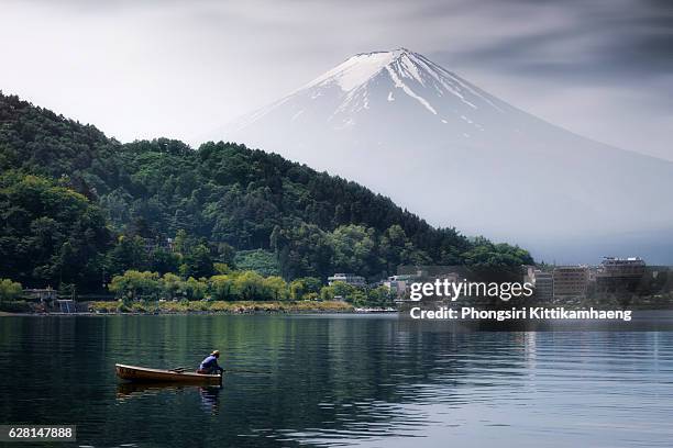 mount fuji at lake kawaguchi in the dark morning with a fisherman - shintoismus stock-fotos und bilder