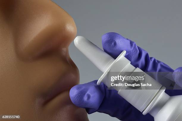 closeup of health worker using nasal spray bottle to administer medicine - vaporizzatore foto e immagini stock