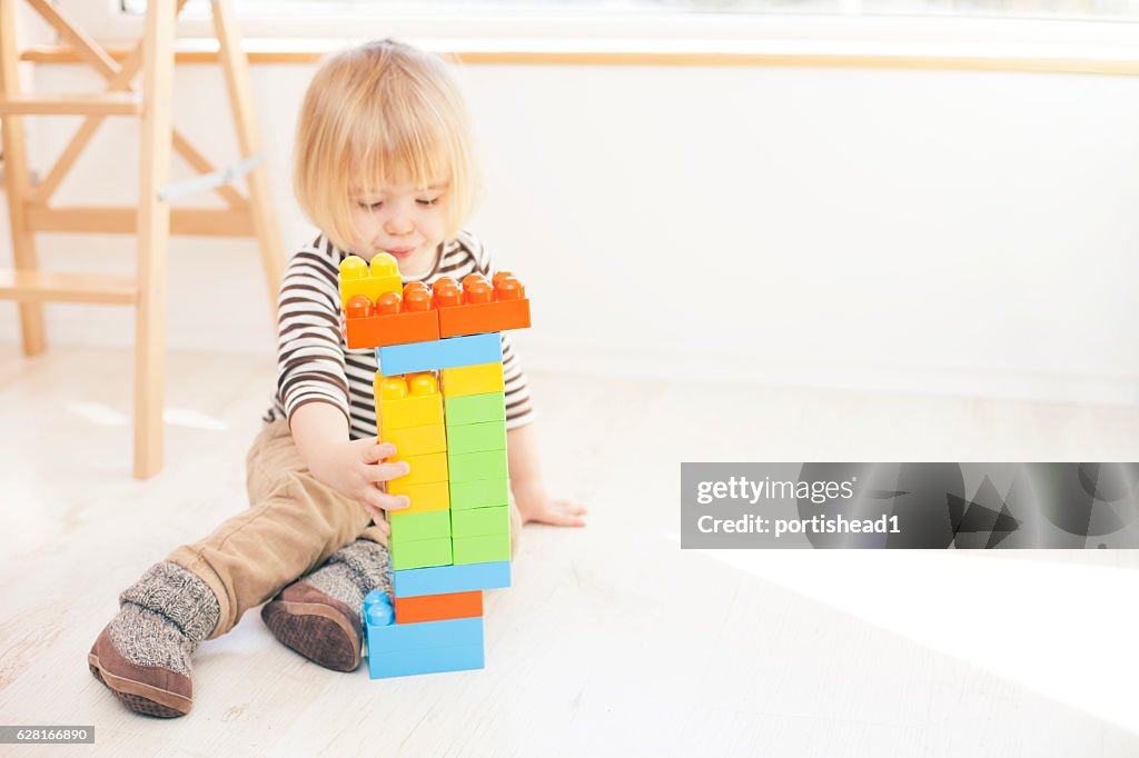 Little child playing with colorful plastic blocks