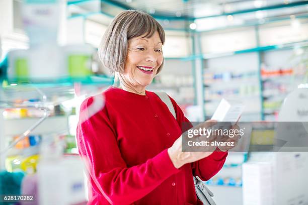 smiling senior woman buying medicine - seniors shopping stock pictures, royalty-free photos & images