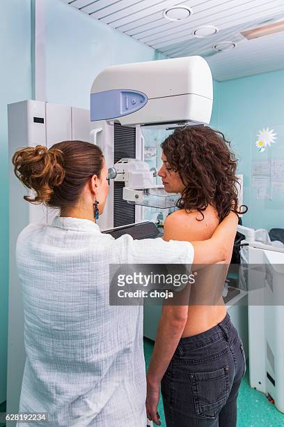 nurse with young women having a mammography - mammogram stockfoto's en -beelden