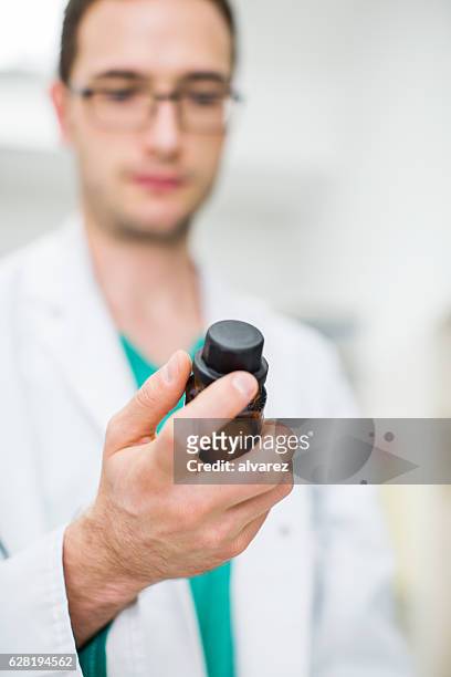 male druggist checking a bottle of tablets - cure berlin 2016 stock pictures, royalty-free photos & images
