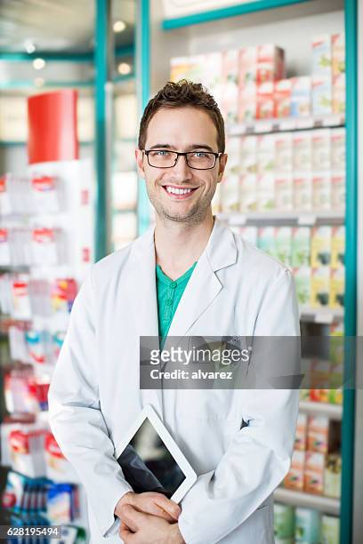 male druggist with digital tablet at chemist store aisle - cure berlin 2016 stock pictures, royalty-free photos & images