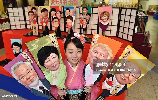 Japanese traditional doll maker Kyugetsu employee Megumi Kondo, in a kimono dress, displays wooden battledores with images of Nintendo President...