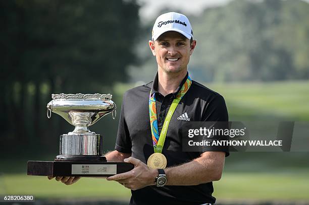 British golfer Justin Rose holds the Hong Kong Open trophy while wearing his Olympic gold medal from the Rio 2016 games in Hong Kong on December 7 a...