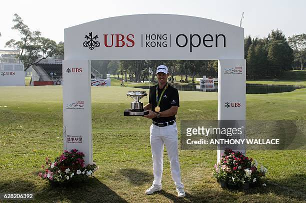 British golfer Justin Rose holds the Hong Kong Open trophy while wearing his Olympic gold medal from the Rio 2016 games in Hong Kong on December 7 a...