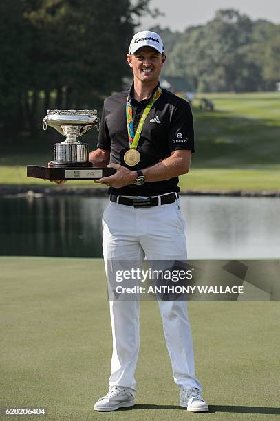 British golfer Justin Rose holds the Hong Kong Open trophy while wearing his Olympic gold medal from the Rio 2016 games in Hong Kong on December 7 a...