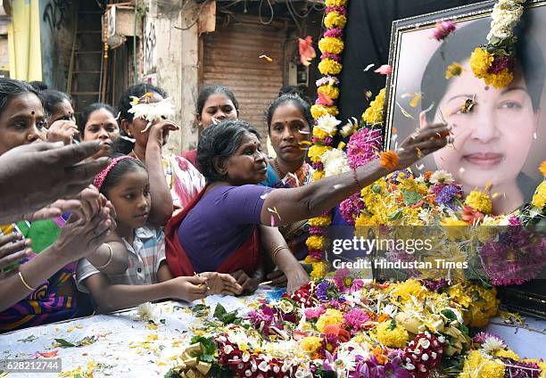 Supporters of Tamil Nadu Chief Minister J Jayalalithaa pay tributes near her photograph outside their party office at Dharavi, on December 6, 2016 in...