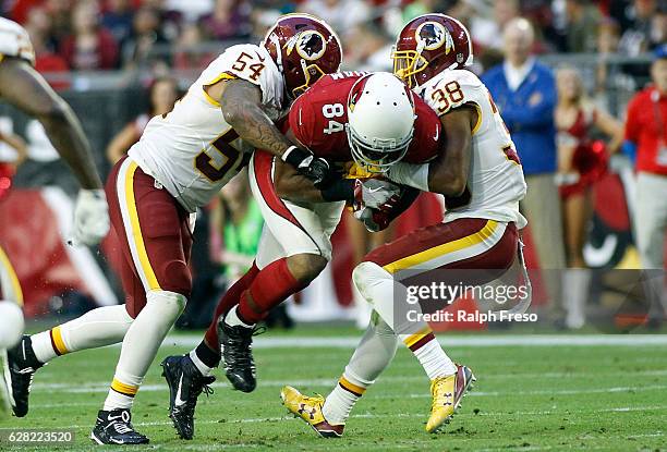 Jermaine Gresham of the Arizona Cardinals is tackled by Mason Foster and Kendall Fuller of the Washington Redskins after a catch during the fourth...