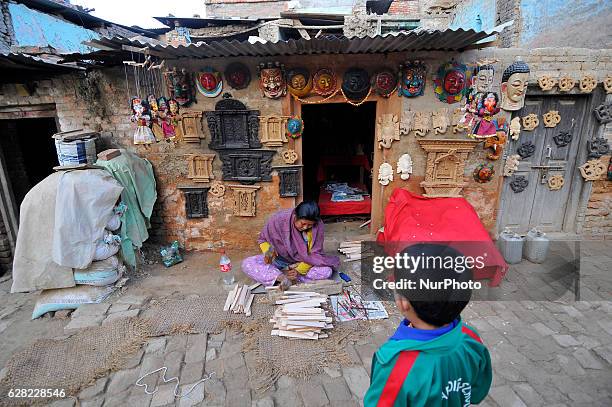 School kid glancing as ASMITA MAHARJAN, 28 yrs. Old, works on her carving business at Khokana, Patan, Nepal on Tuesday, December 06, 2016. Although...