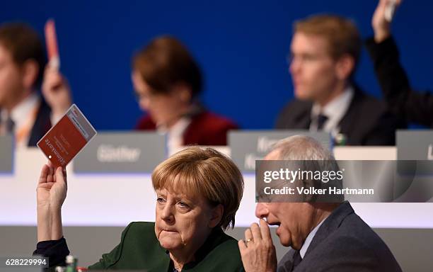Chancellor and Chairwoman of the German Christian Democrats Angela Merkel holds a voting card next to the Federal Minister for Finance, Wolfgang...