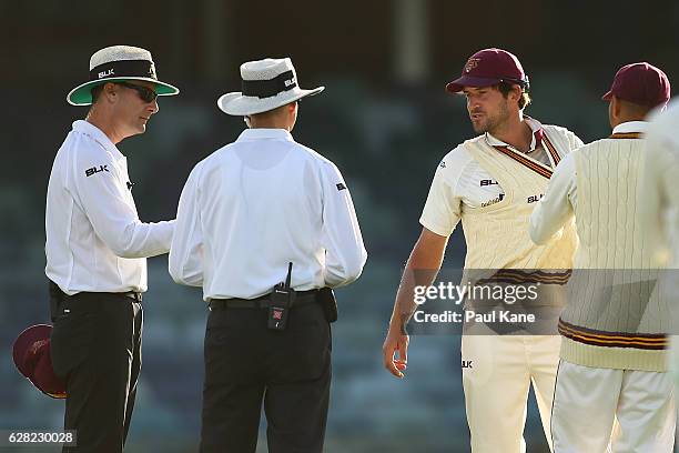 Joe Burns of Queensland is pulled away by Usman Khawaja after having discussions with match umpires Geoff Joshua and Phillip Gillespie following an...