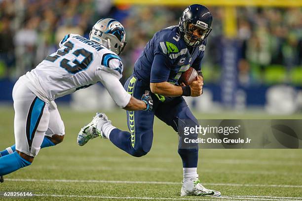 Quarterback Russell Wilson of the Seattle Seahawks rushes against cornerback Leonard Johnson of the Carolina Panthers at CenturyLink Field on...