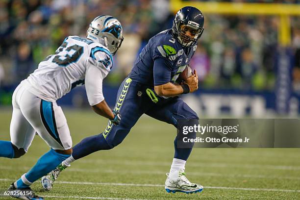 Quarterback Russell Wilson of the Seattle Seahawks rushes against cornerback Leonard Johnson of the Carolina Panthers at CenturyLink Field on...