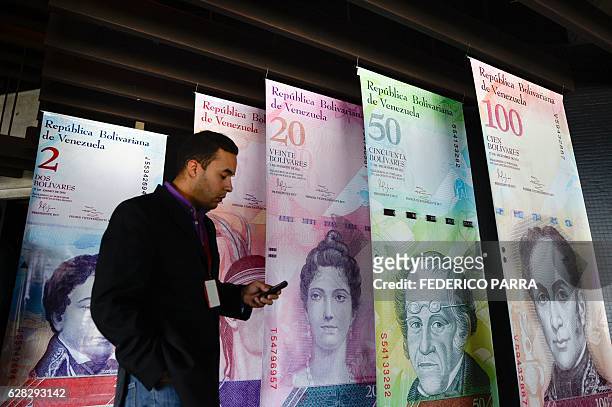 Man walks past banners showing Venezuela's currency, the bolivar, at the Central Bank of Venezuela in Caracas on December 7, 2016. The BCV on...