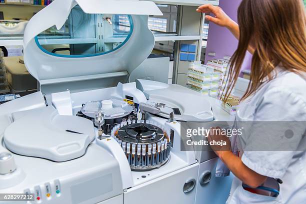 lab scientist placing test tubes with blood samples in centrifuge - centrifugal force stockfoto's en -beelden