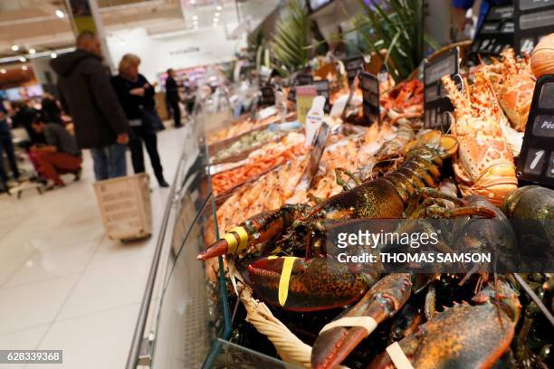 People look at the fresh fish and crustacean section of an hypermarket store of French retail giant Carrefour, in Villeneuve-la-Garenne, near Paris,...