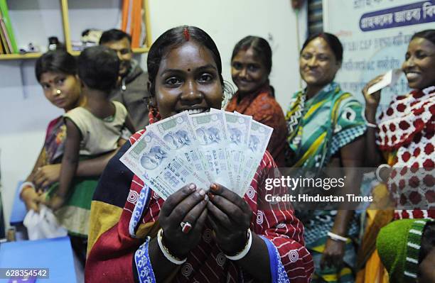 Bank customer is showing 100 rupee notes as she was waiting since midnight at SBI customer service point, Laxbagan, Satjelia island on December 5,...