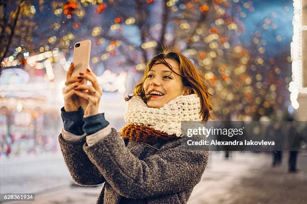woman taking selfies on the christmas decorated street - christmas travel stock pictures, royalty-free photos & images