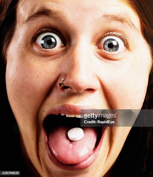 chica bonita y muy emocionada mostrando una píldora en la lengua - acid fotografías e imágenes de stock