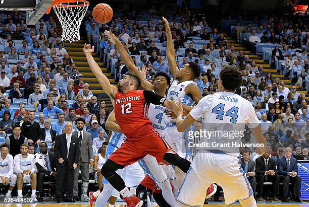 Jack Gibbs of the Davidson Wildcats drives against Isaiah Hicks and Nate Britt of the North Carolina Tar Heels during the game at the Dean Smith...