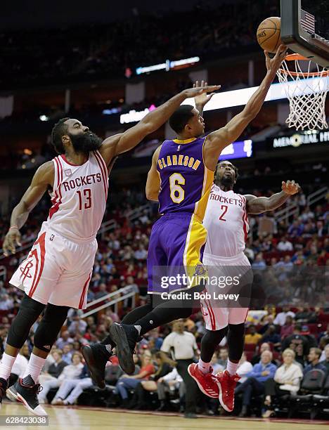 Jordan Clarkson of the Los Angeles Lakers drives to the basket between James Harden of the Houston Rockets and Patrick Beverley at Toyota Center on...