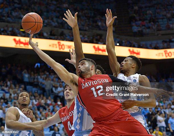 Jack Gibbs of the Davidson Wildcats drives against Isaiah Hicks and Nate Britt of the North Carolina Tar Heels during the game at the Dean Smith...