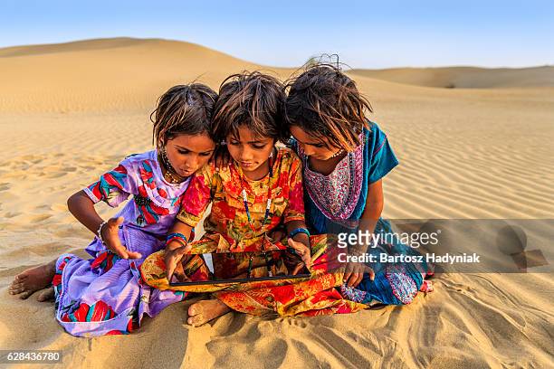 happy indian little girls using digital tablet, desert village, india - local gypsy stock pictures, royalty-free photos & images