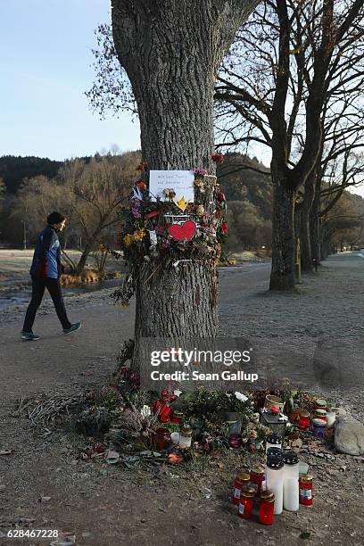 Woman, who said she did not mind being photographed, walks past flowers and messages left by mourners that adorn a tree near the spot where Maria L.,...