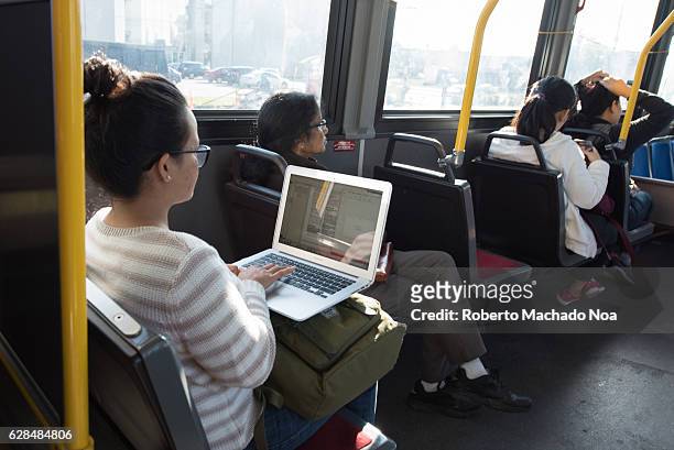 Student or young woman using laptop inside a TTC bus. Inside of public transport. A girl using her portable computer inside the bus.