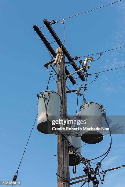 Electric transformer in urban pole. Electric post with cables and three cylinder transformers.