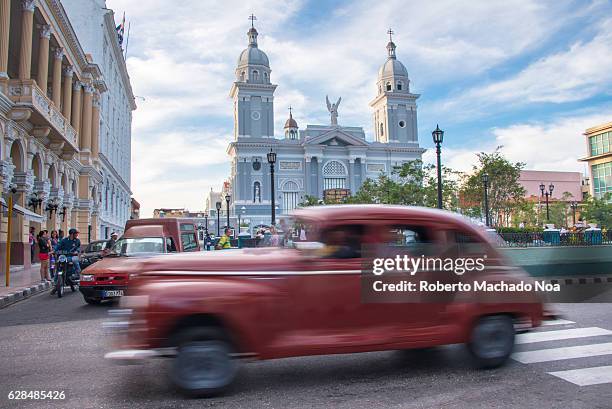 Cathedral Our Lady of Asuncion in the Cespedes plaza. Old American car as taxi and moving in the tropical city. The church and old cars are a major...