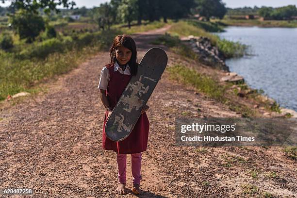 Young girl in school dress poses with her skate board on October 26, 2016 in Janwaar, India. Thanks to a German community activist and author Ulrike...