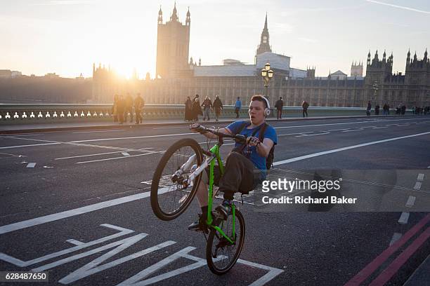 Youth balances on his rear wheel to perform a wheelie on the South side of Westminster Bridge, on 30th November 2016, in London England. Across the...