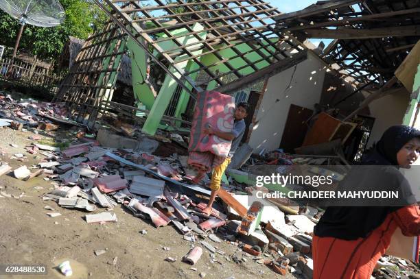 Villagers salvage goods from their house which was damaged in an earthquake in Kuta Pangwa village in Pidie Jaya on December 8, 2016. - Every house...