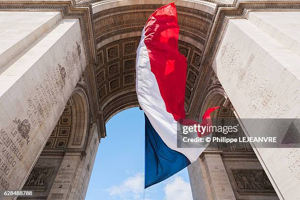 french flag floating under the triumphal arch in paris, france - bastille day stock pictures, royalty-free photos & images