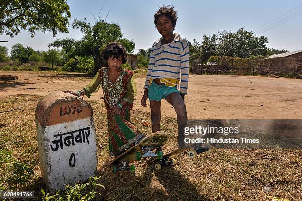 Young boy and a girl pose with their skateboards near Zero milestone of village on October 26, 2016 in Janwaar, India. Thanks to a German community...