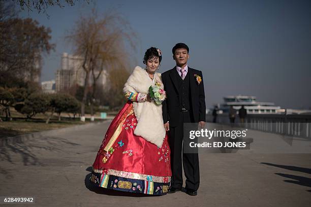 In this photo taken on November 25 groom Sip Seung-chul stands with his bride as they prepare to attend a wedding photo shoot on the Taedong river in...