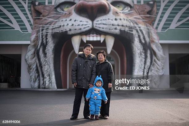 In this photo taken on November 27 toddler Mun Ji-Song poses for a photo with his parents at the entrance to the Central Zoo in Pyongyang. / AFP / Ed...