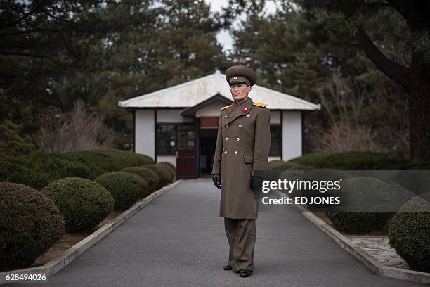 In this photo taken on November 30 Korean People's Army liutenant and tour guide Hwang Myong-Jin poses for a photo in front of a hut where...