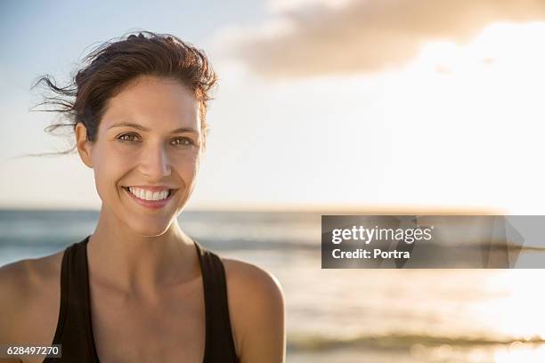 happy young woman at beach during sunset - sportbeha stockfoto's en -beelden