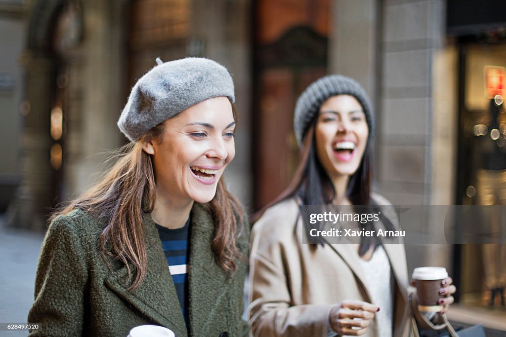 Cheerful shopaholic female friends on city street