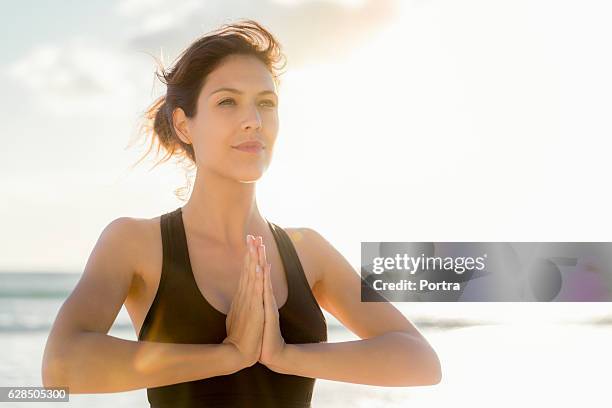 sportler steht in gebetsposition am strand - namaste stock-fotos und bilder