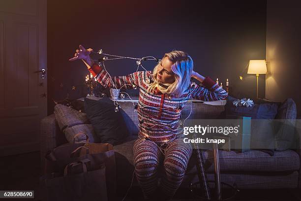 christmas woman at home with christmas lights tangled - christmas funny stockfoto's en -beelden