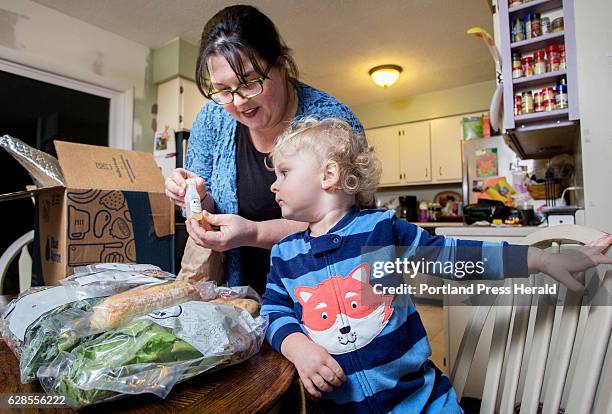 Emily Griffin unpacks a box from the Blue Apron meal service as her two-year-old son Everett looks on.