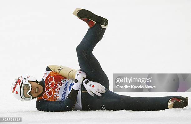 Russia - Taihei Kato of Japan holds his left arm after crash-landing in the ski jumping portion of the Nordic combined individual large hill...