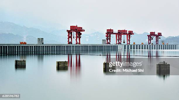 a sublime landscape expansive view of china's three gorges dam on the yangtze river in diffused soft light with reflections of the dam in the water showcasing the zen-like tranquility. - dam china 個照片及圖片檔