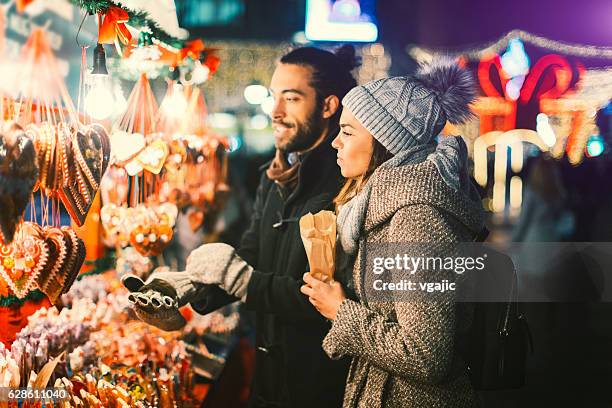 giovane coppia che si diverte all'aperto a natale - mercatini di natale foto e immagini stock