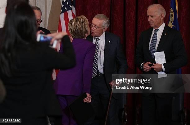 Former U.S. Secretary of State Hillary Clinton kisses Senate Minority Leader Sen. Harry Reid after her remarks as Vice President Joseph Biden looks...